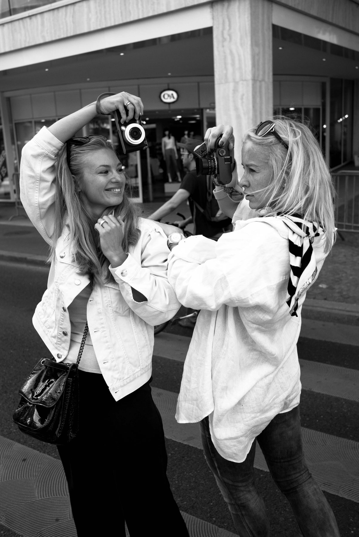 Two women photographing each other in the street during a lesson
