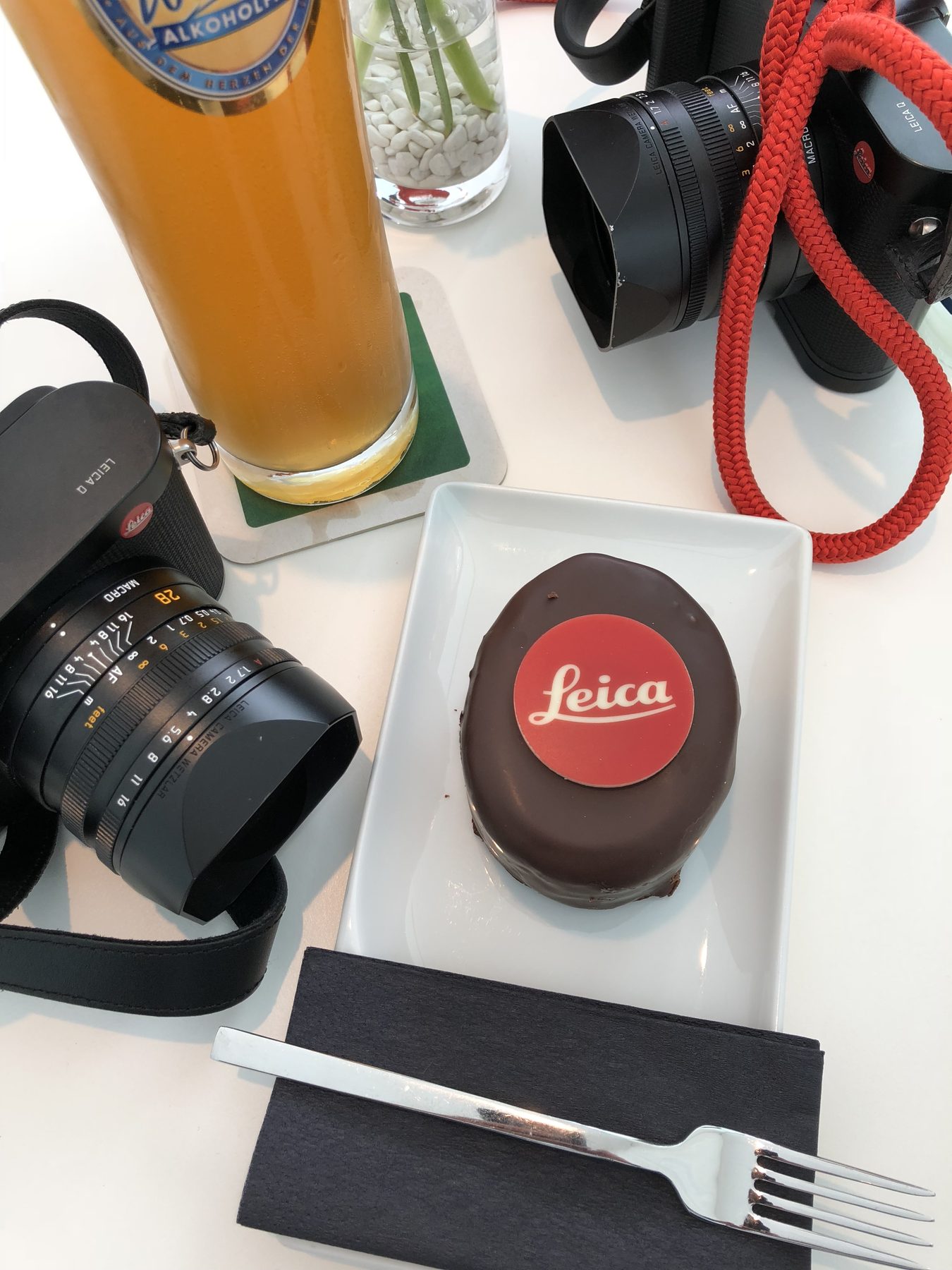 A chocolate cake with the Leica logo next to a camera and lens